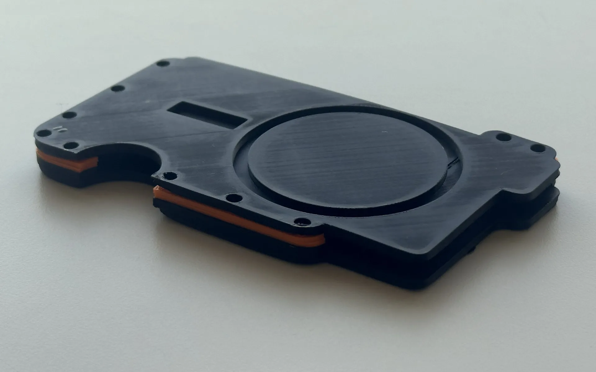 Prototype 1, 3D printed in black with orange layers, phone side up: magnet ring recess and screw holes.